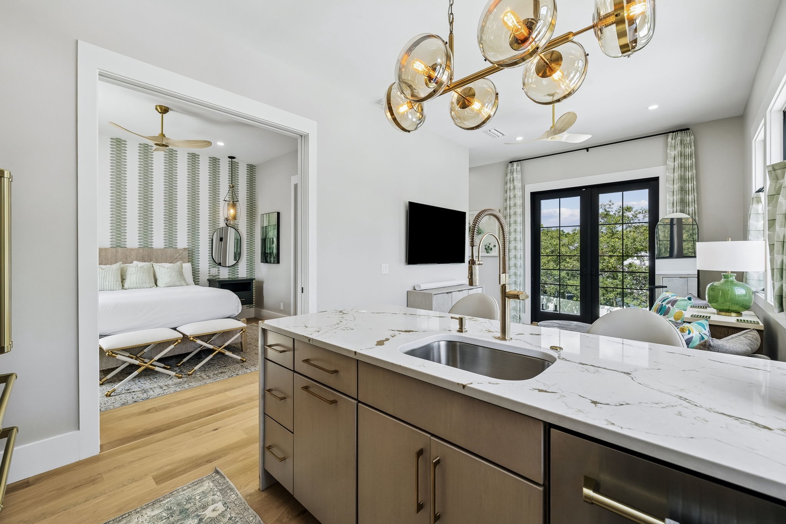 Step into this elegant suite where modern sophistication meets comfort. The open layout connects a stylish kitchenette to the serene bedroom, with natural light flooding through glass doors and warm finishes throughout.