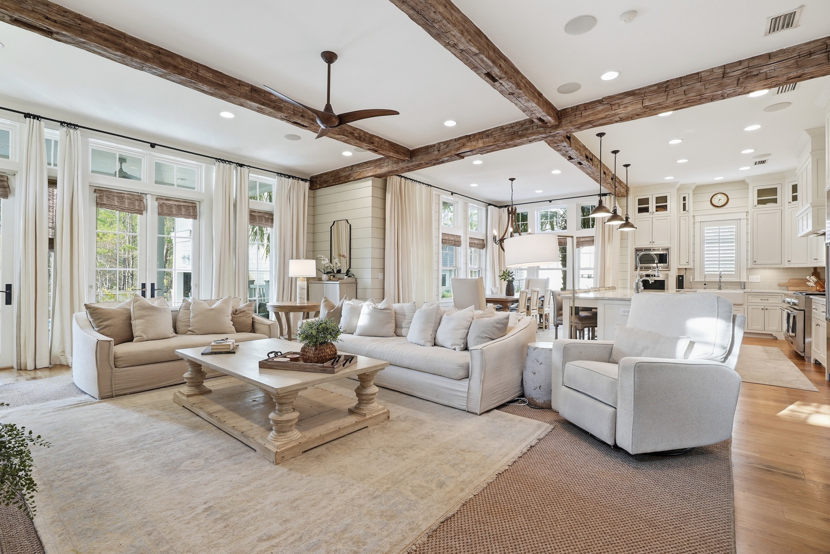 Relax in this spacious open-concept living area where rustic beams meet modern elegance. Sunlight streams through large windows, creating a warm, inviting atmosphere perfect for your getaway.