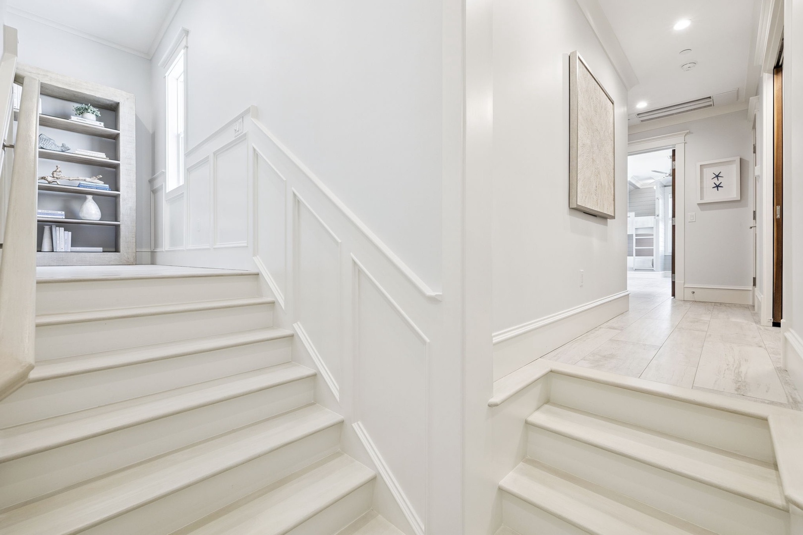 Elegant white staircase with custom built-ins creates your welcoming entry, leading to bright spaces above.