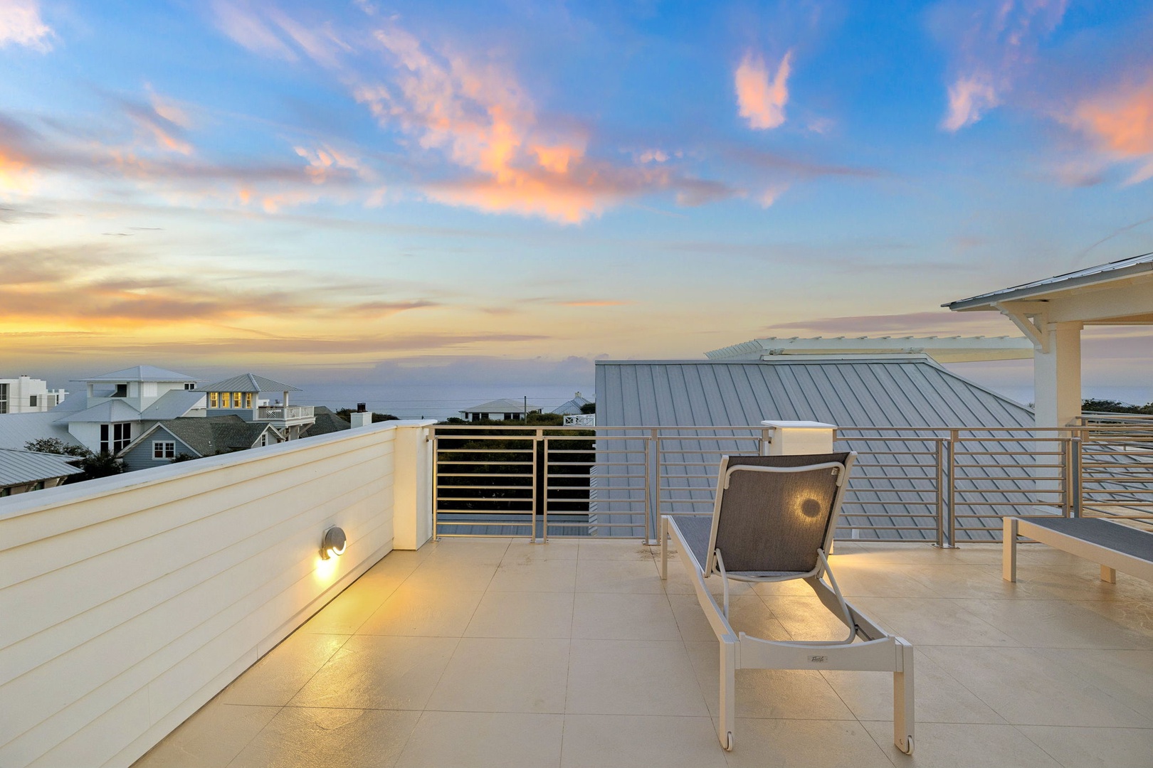 Rooftop terrace with modern seating overlooking a residential neighborhood during golden hour.