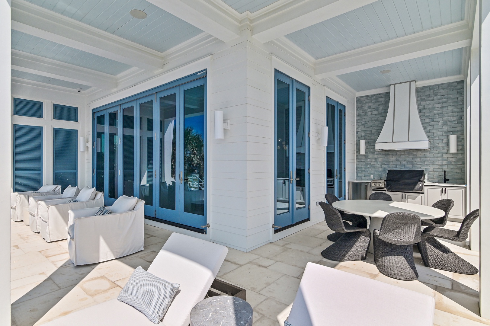 Relax in your covered outdoor living space, complete with plush lounge seating, dining area, and built-in grill—perfect for entertaining or unwinding in coastal comfort.