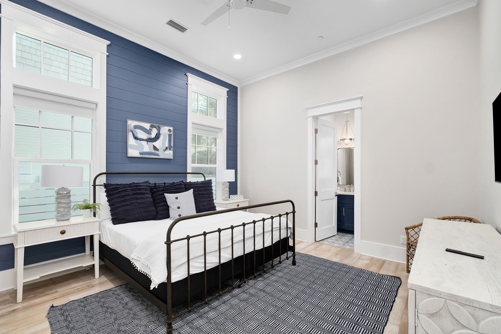 Sink into crisp white linens and navy pillows in this stylish bedroom, where the bold accent wall creates a cozy retreat for your restful nights.