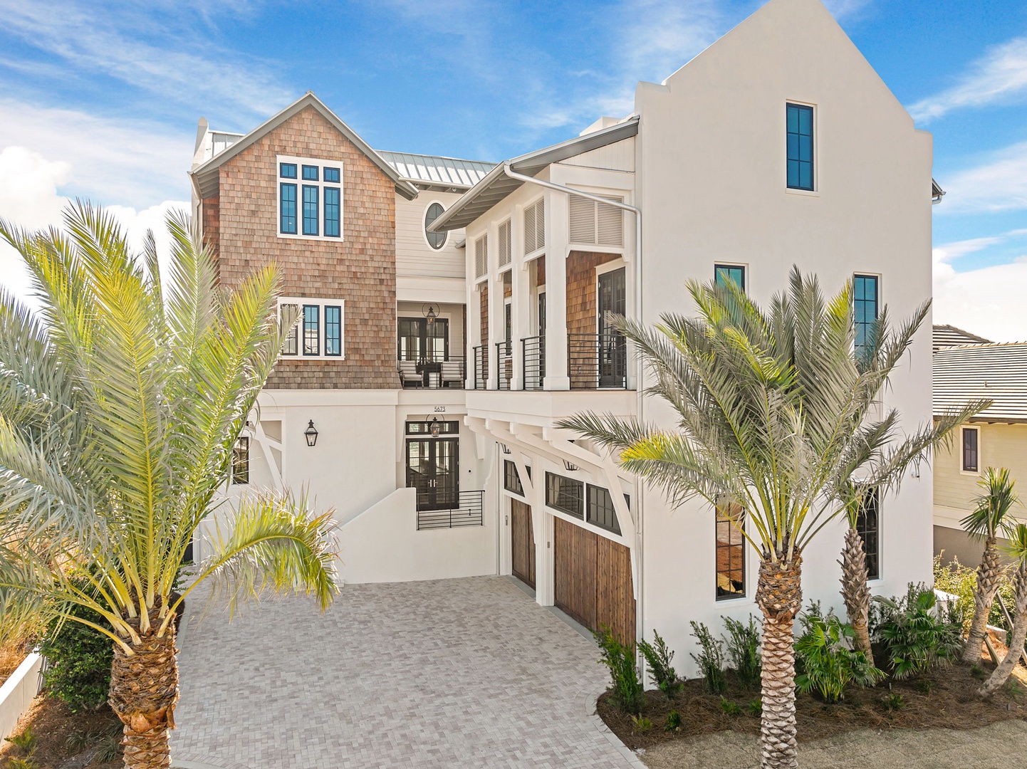 Modern coastal architecture with tropical palms creates an elegant beachside retreat in this stunning three-story home.