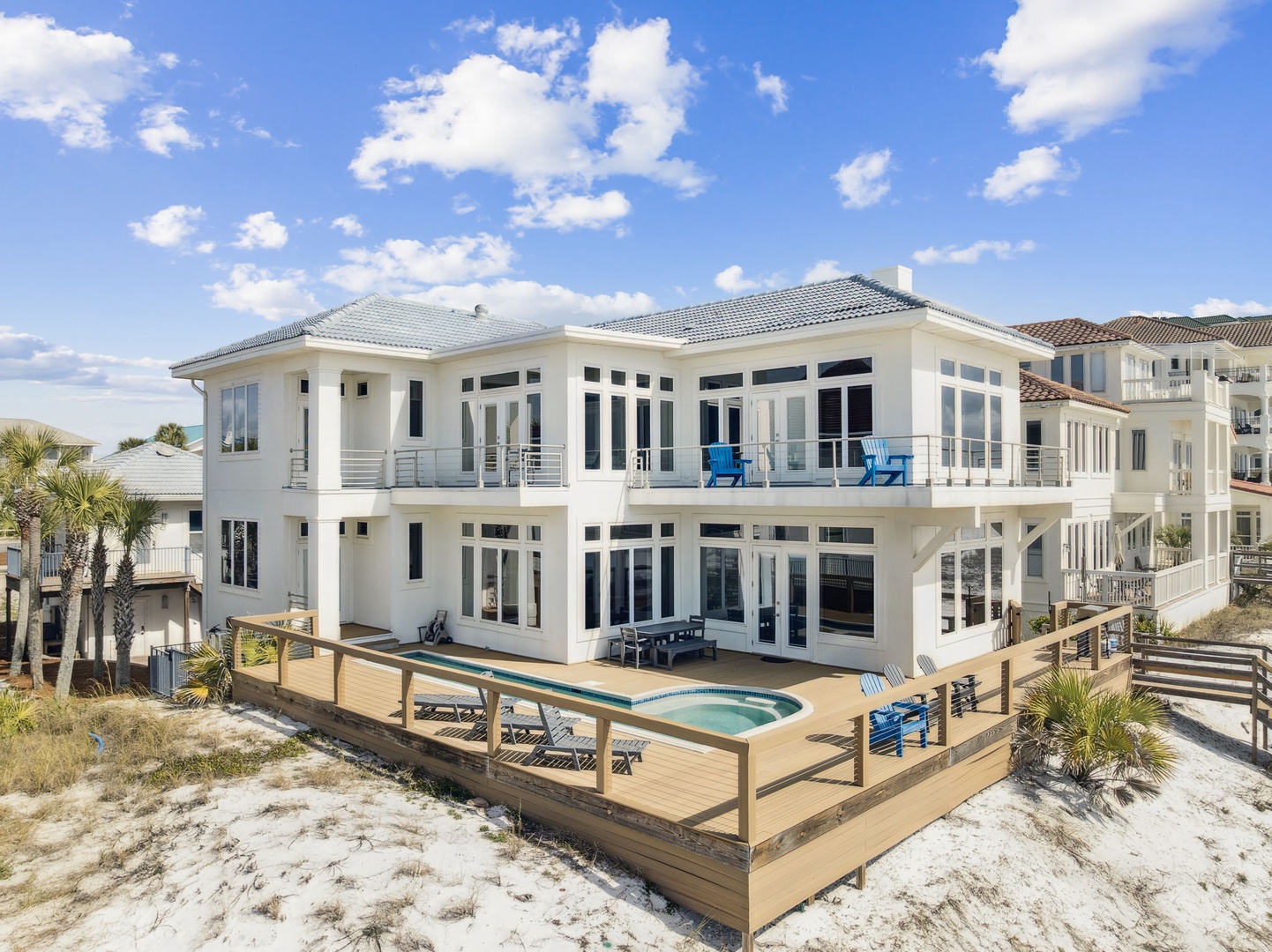 This stunning beachfront home features expansive windows, wraparound decks, and a private pool surrounded by pristine white sand dunes.