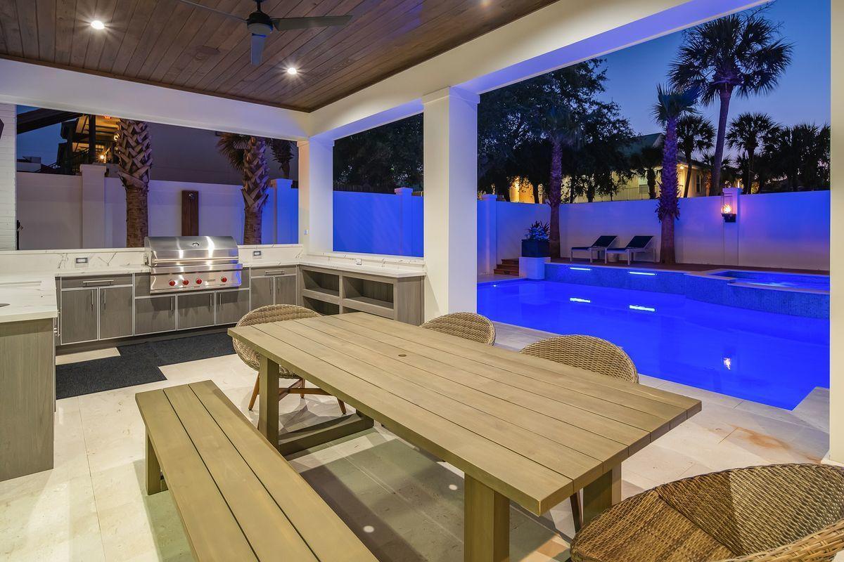 Your outdoor kitchen overlooks a stunning blue-lit pool, perfect for evening entertaining under the stars.