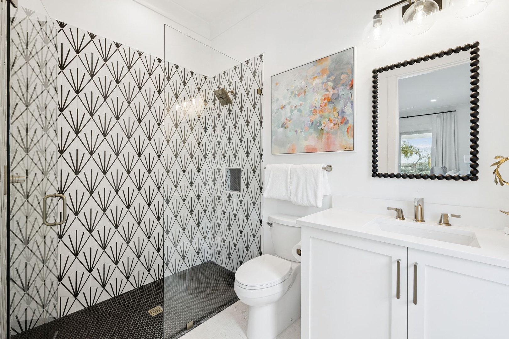 Refresh in your stylish bathroom featuring geometric wallpaper, marble vanity, and a spacious glass shower with luxurious finishes.
