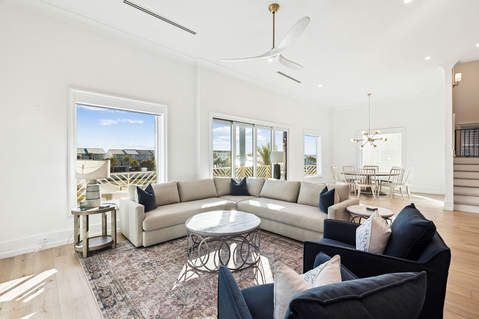 Relax in this bright, modern living space featuring plush sectional seating, elegant decor, and stunning views through floor-to-ceiling windows.