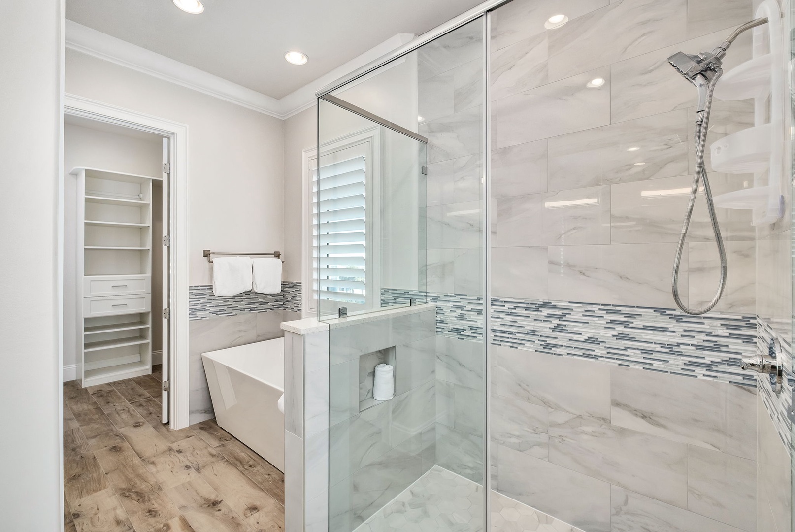 Indulge in your private spa-like bathroom featuring marble finishes, glass shower, and elegant mosaic accents.