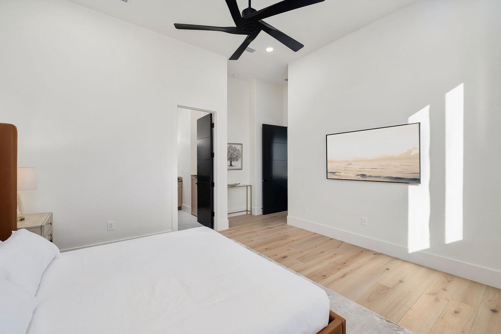 Unwind in your serene bedroom with soaring ceilings, modern ceiling fan, and calming artwork that creates the perfect retreat.