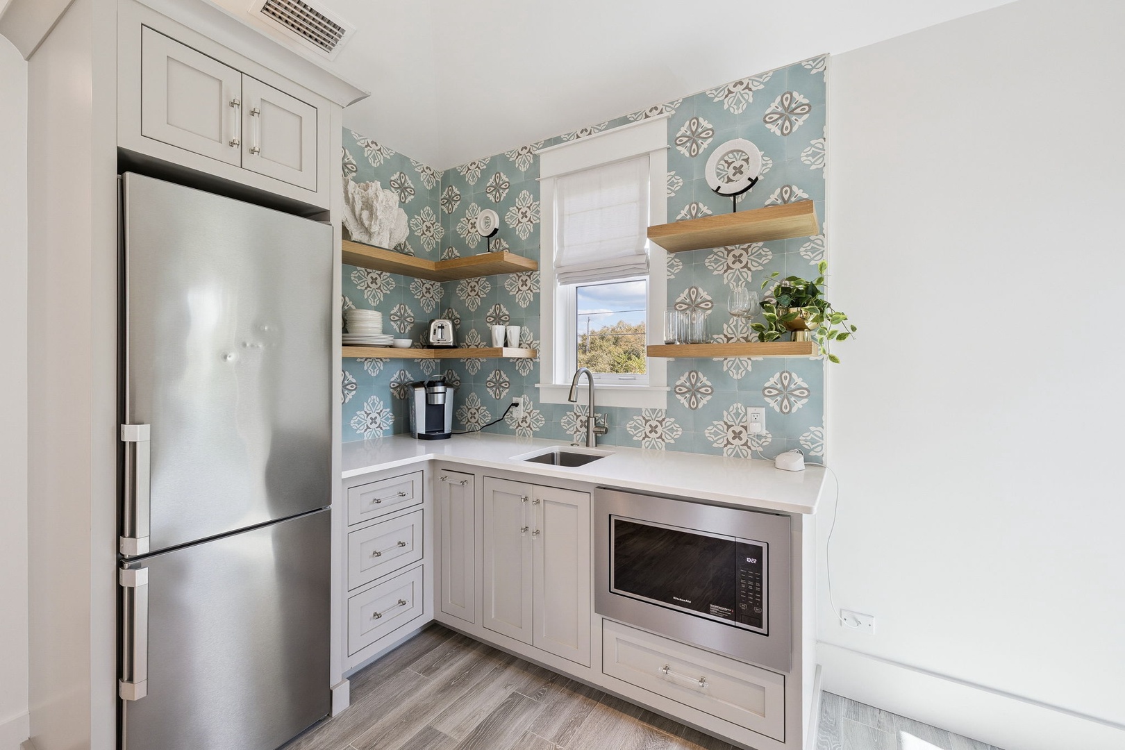 Your bright kitchenette features beautiful patterned tiles, stainless steel appliances, and floating shelves for all your cooking needs.