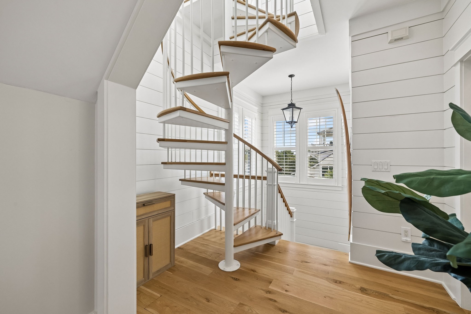 Step inside to discover a bright coastal-inspired space where a charming spiral staircase invites you to explore the upper level, surrounded by crisp white shiplap and warm hardwood underfoot.