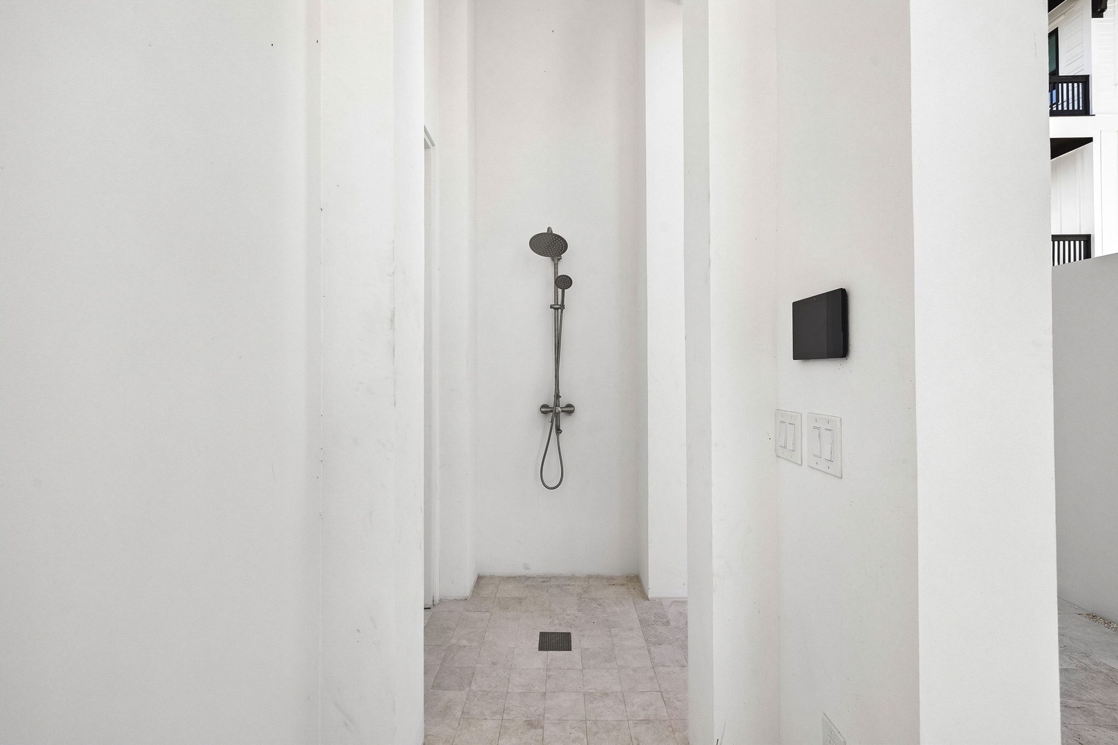 Rinse off in your private outdoor shower surrounded by bright walls and tile, with modern fixtures for a refreshing open-air experience.