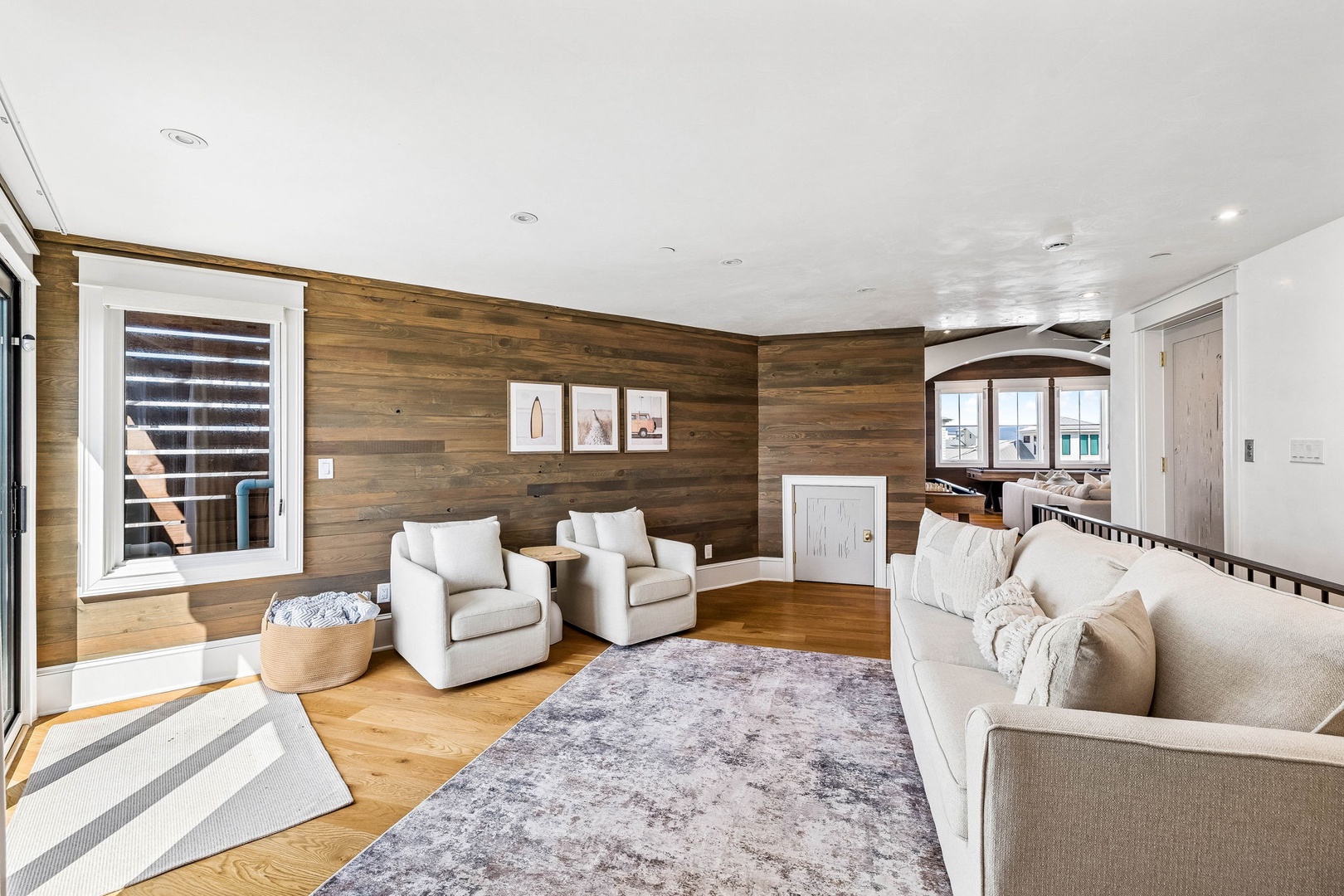 Sink into plush seating in this bright, stylish living room featuring warm wood accent walls and plenty of natural light for your perfect retreat.