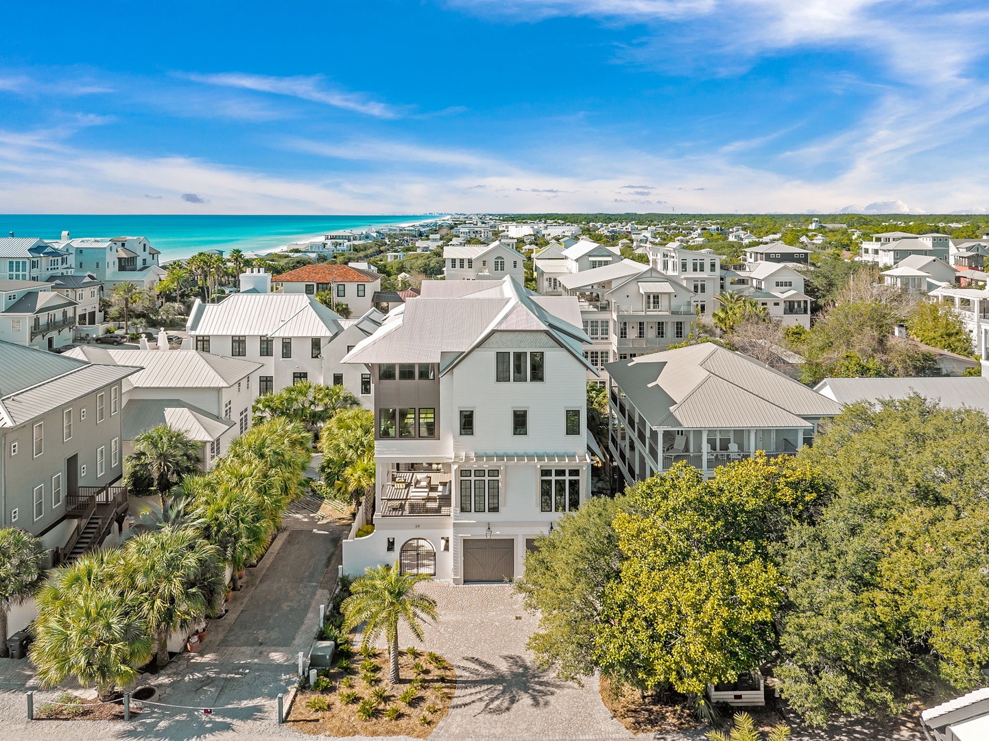 Aerial view of coastal luxury home with pristine turquoise waters and charming beach community nearby.