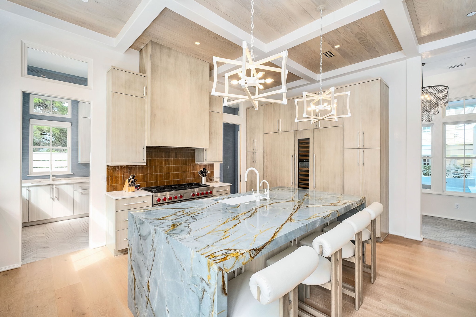 Your gourmet kitchen awaits with a stunning marble waterfall island, professional-grade appliances, and custom cabinetry under soaring coffered ceilings that blend elegance with comfort.