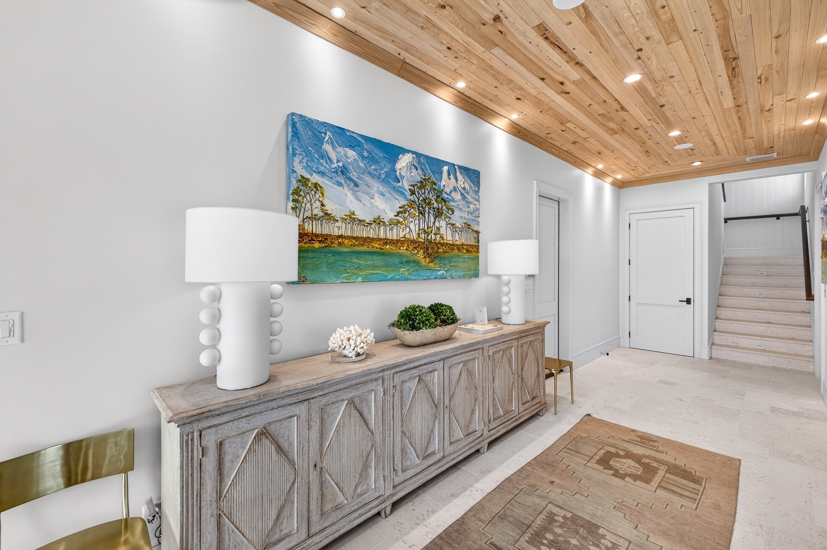 Relax in your stylish living space featuring warm wood ceilings, coastal artwork, and elegant furnishings that create the perfect backdrop for unwinding.