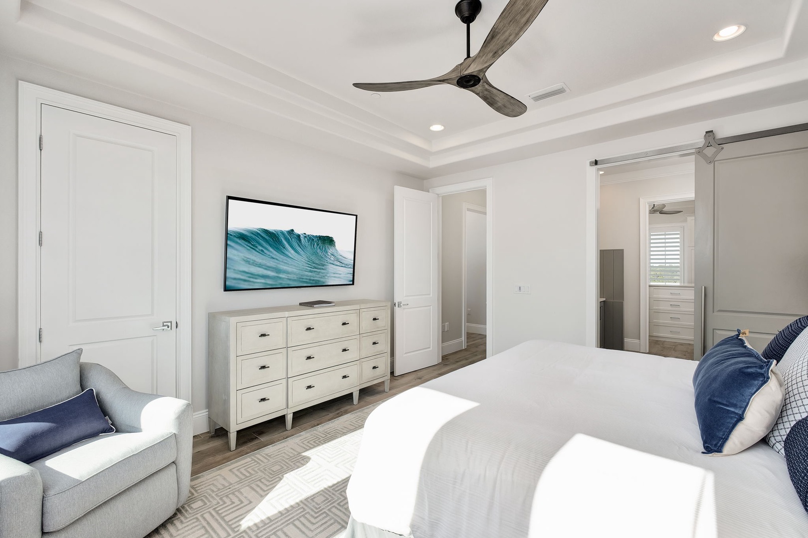 Rest in your serene master suite with plush bedding, coastal art, and a cozy reading chair for quiet moments.