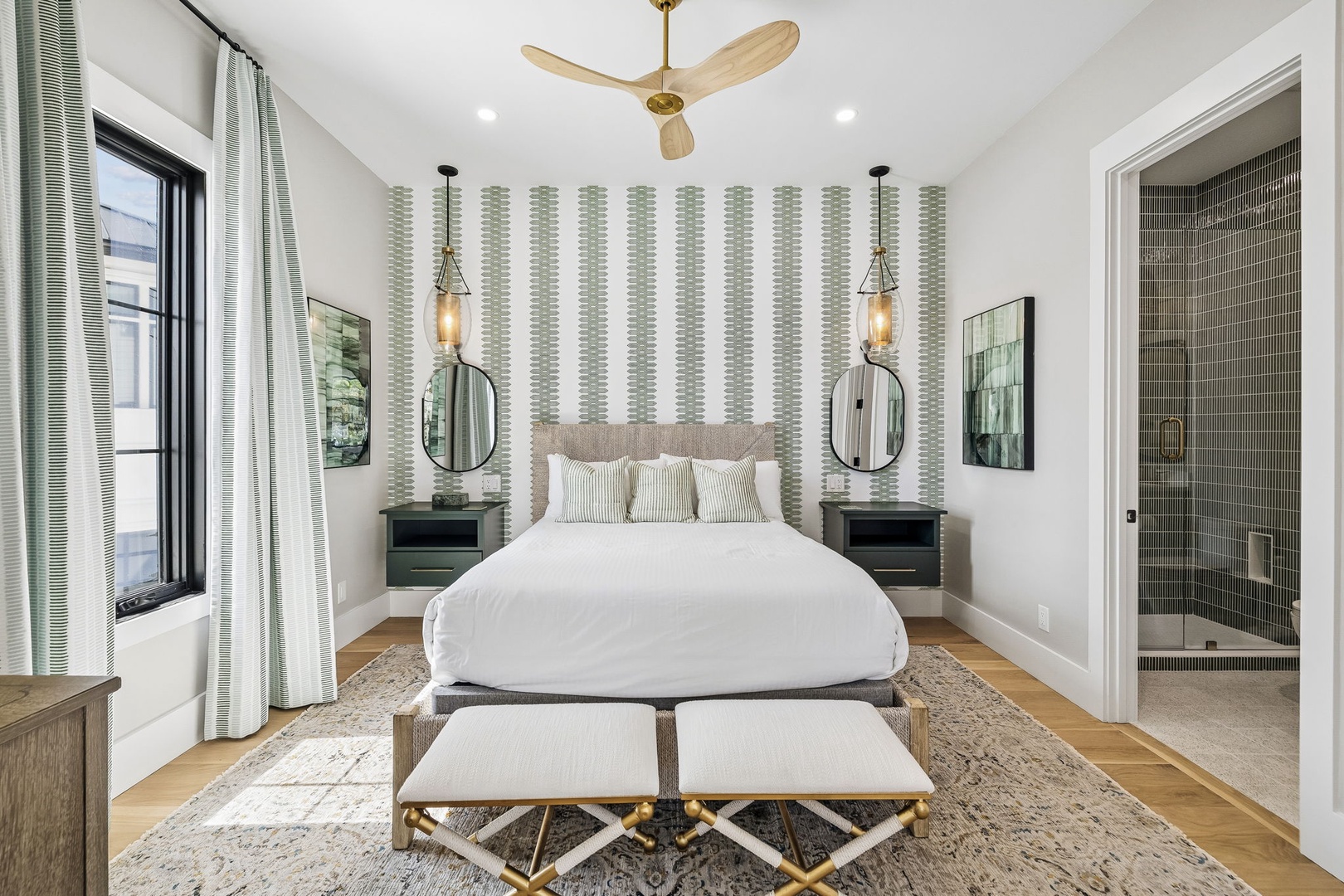Sink into crisp white linens and unwind in your serene bedroom retreat. Natural wood tones and gentle green accents create a calming atmosphere, while an ensuite bathroom awaits just steps away.