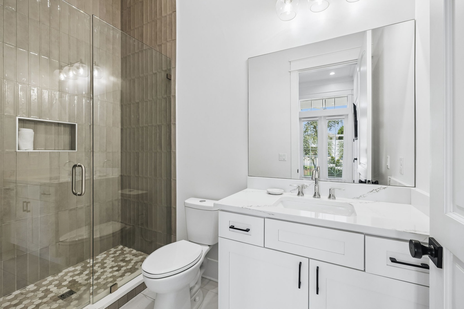 Freshen up in your spa-inspired bathroom, featuring a spacious walk-in shower with elegant tiling, a well-lit vanity with marble countertops, and modern fixtures throughout.