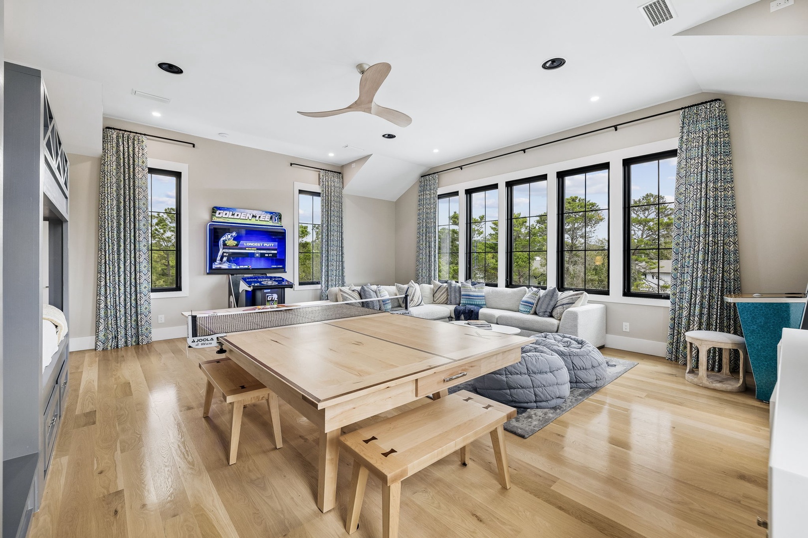 A sunlit retreat where you'll love gathering with friends and family. The bright, open living space features vaulted ceilings, wraparound windows framing lush greenery, and a versatile game table perfect for lively evenings or cozy mornings together.