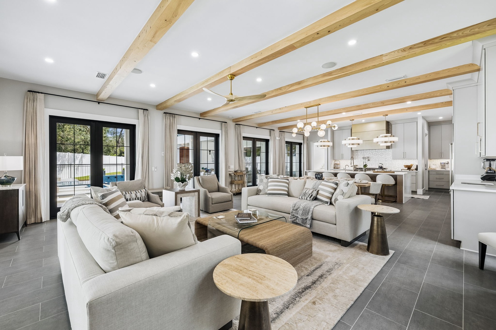 Relax into comfort in this beautifully designed open living space, where vaulted ceilings with warm wood beams draw the eye upward and natural light pours in through elegant French doors leading to your private outdoor retreat.