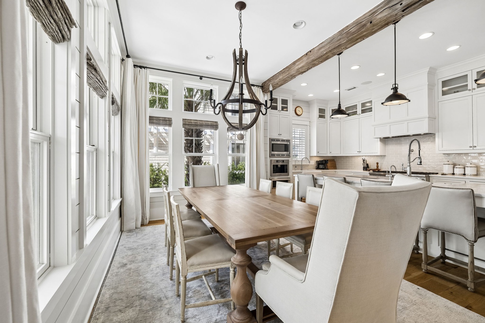 Step into a bright, open kitchen and dining area with charming rustic beams, elegant lighting, and a spacious table perfect for sharing meals with your travel companions.