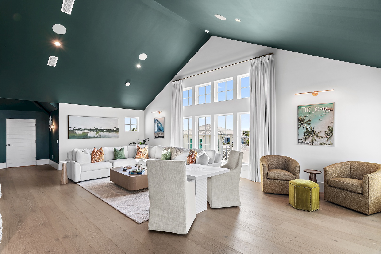Sink into plush seating and enjoy natural light streaming through soaring windows, framing views of the neighborhood. Your coastal retreat awaits in this bright, airy living space.