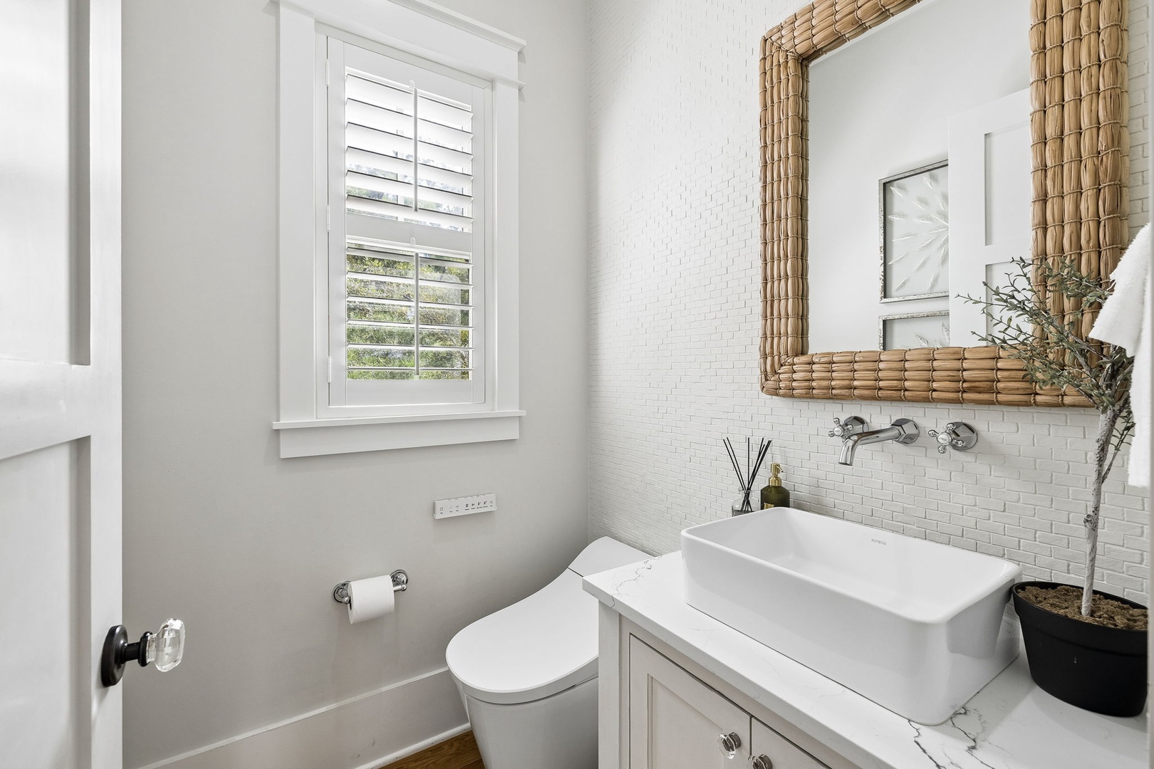 Refresh in your stylish bathroom with its crisp white tile, natural woven mirror, and modern vessel sink—everything thoughtfully arranged for your comfort.