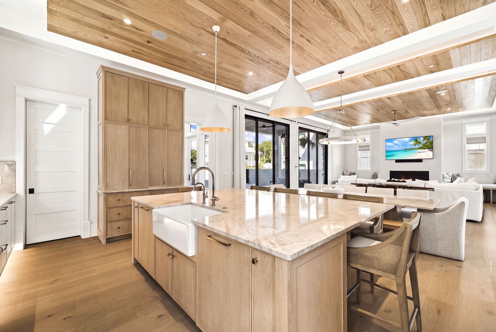 Step into this open-concept living space where natural wood tones and vaulted ceilings create a warm, airy retreat. The kitchen island invites you to gather while sunlight pours through glass doors beyond.