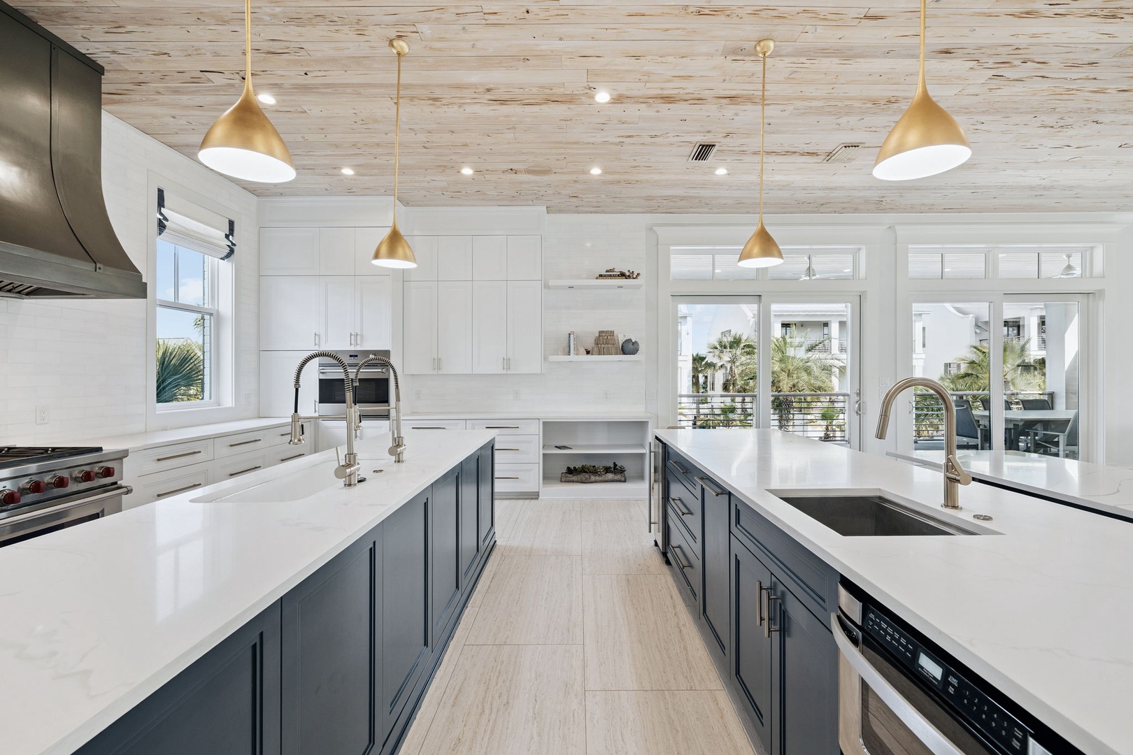 Your gourmet kitchen features dual islands, brass pendant lights, and stunning views through floor-to-ceiling windows.
