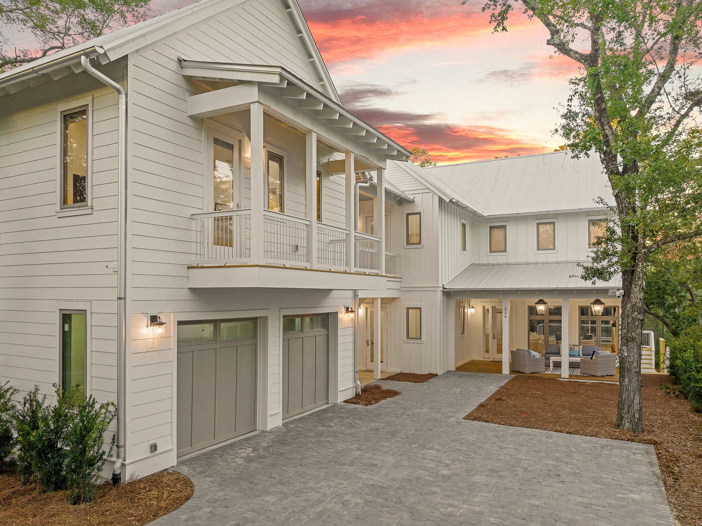 A modern farmhouse retreat featuring clean lines and warm lighting against a stunning sunset backdrop.