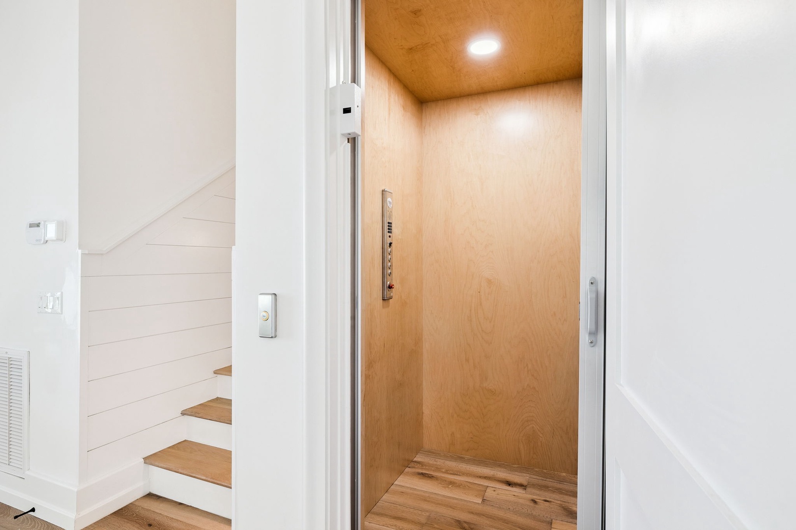 Step into your private elevator that whisks you directly to your door—modern convenience meets sleek design in warm wood tones.