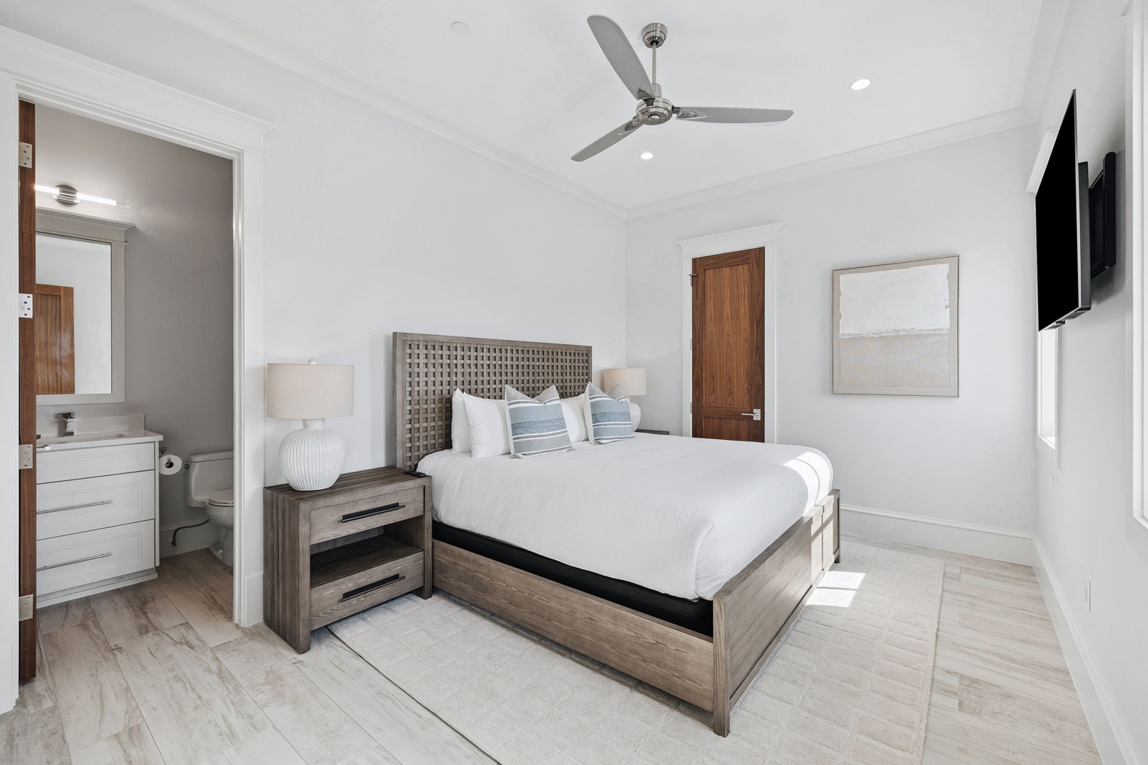 Sink into crisp white linens and modern comfort in your stylish bedroom, complete with ceiling fan and en-suite convenience.
