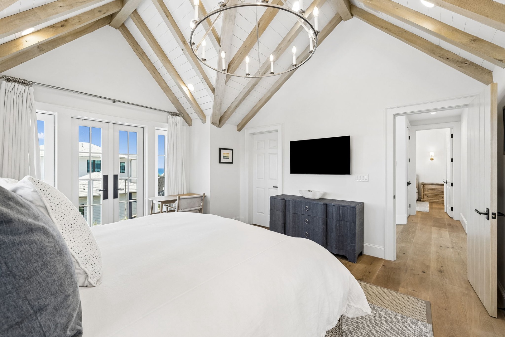 Drift off beneath soaring cathedral ceilings and rustic beams as natural light pours through French doors, framing waterfront views. Your private retreat balances coastal charm with modern comfort.