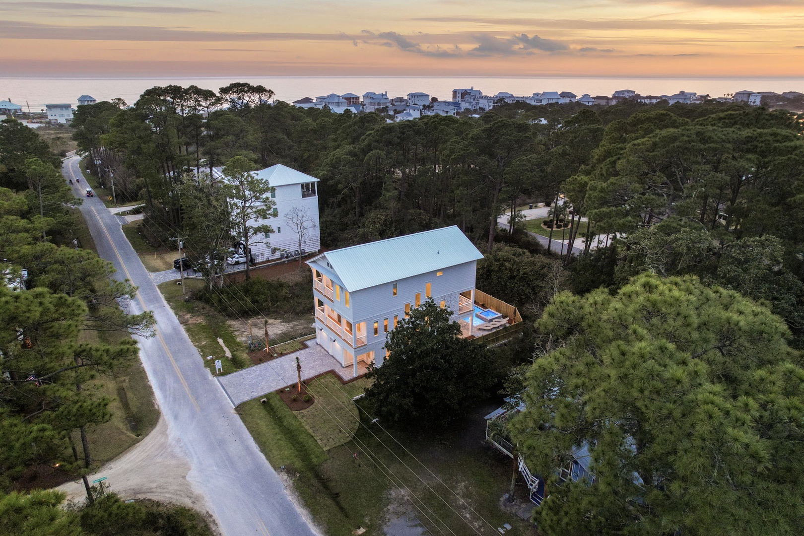 Modern coastal retreat nestled among lush trees, just minutes from the beach with ocean views on the horizon.