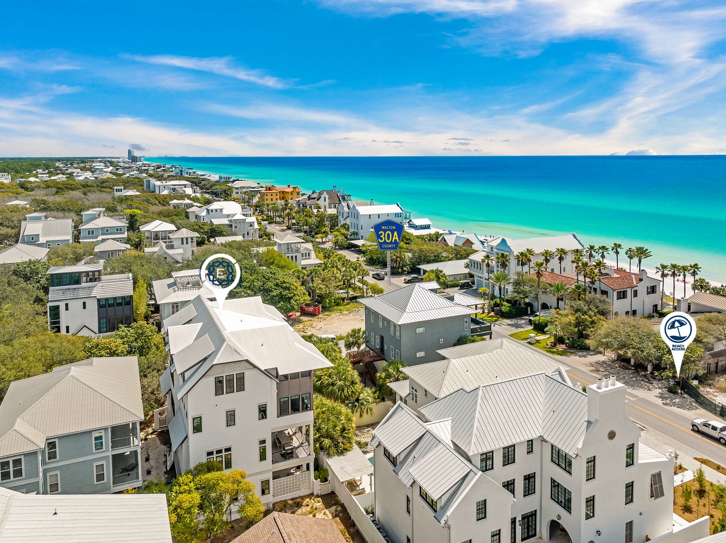 Aerial view of the coastal neighborhood showing vacation rental properties just steps from pristine turquoise waters and white sand beaches.