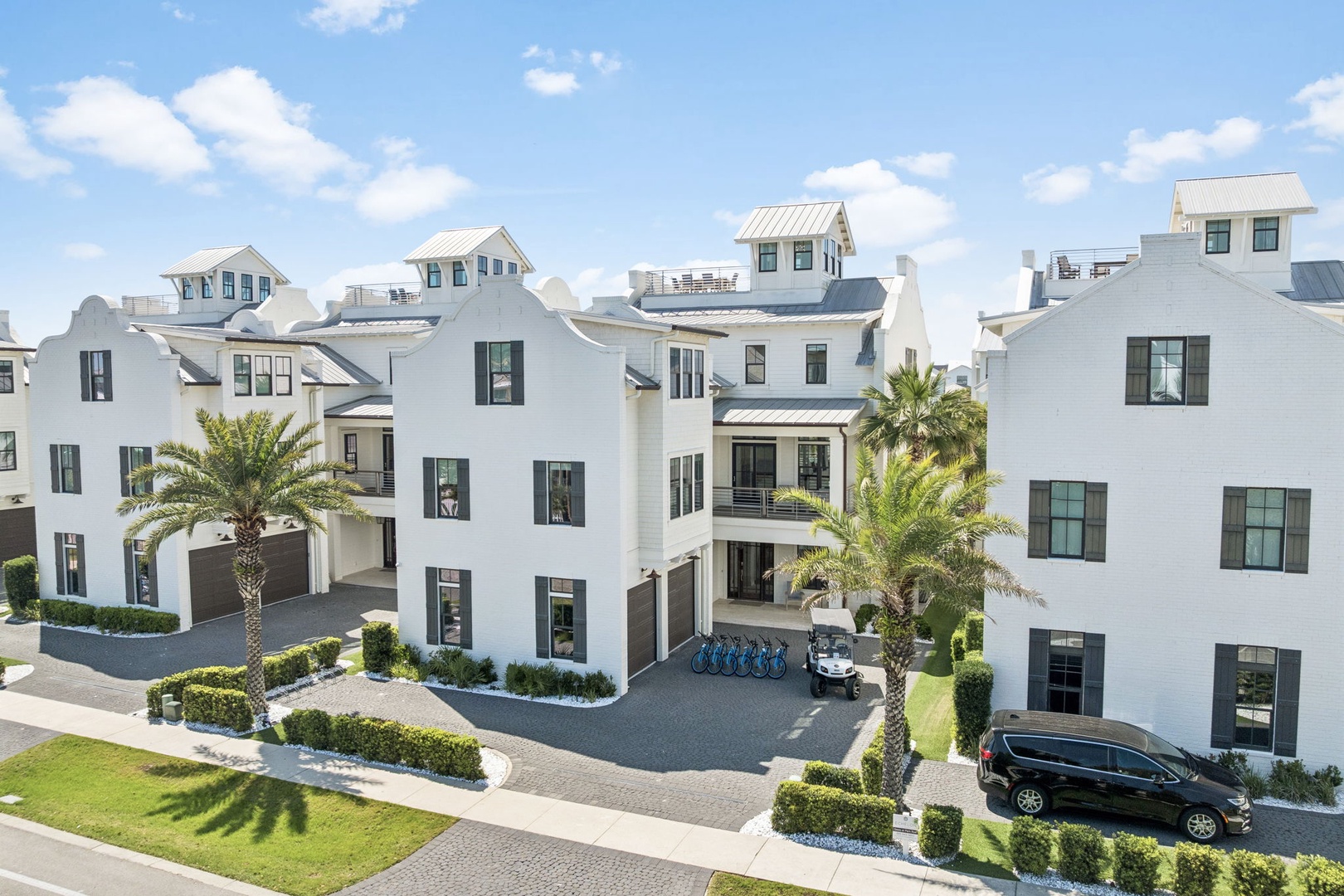 Modern white residential complex with palm trees and manicured landscaping in a coastal setting.