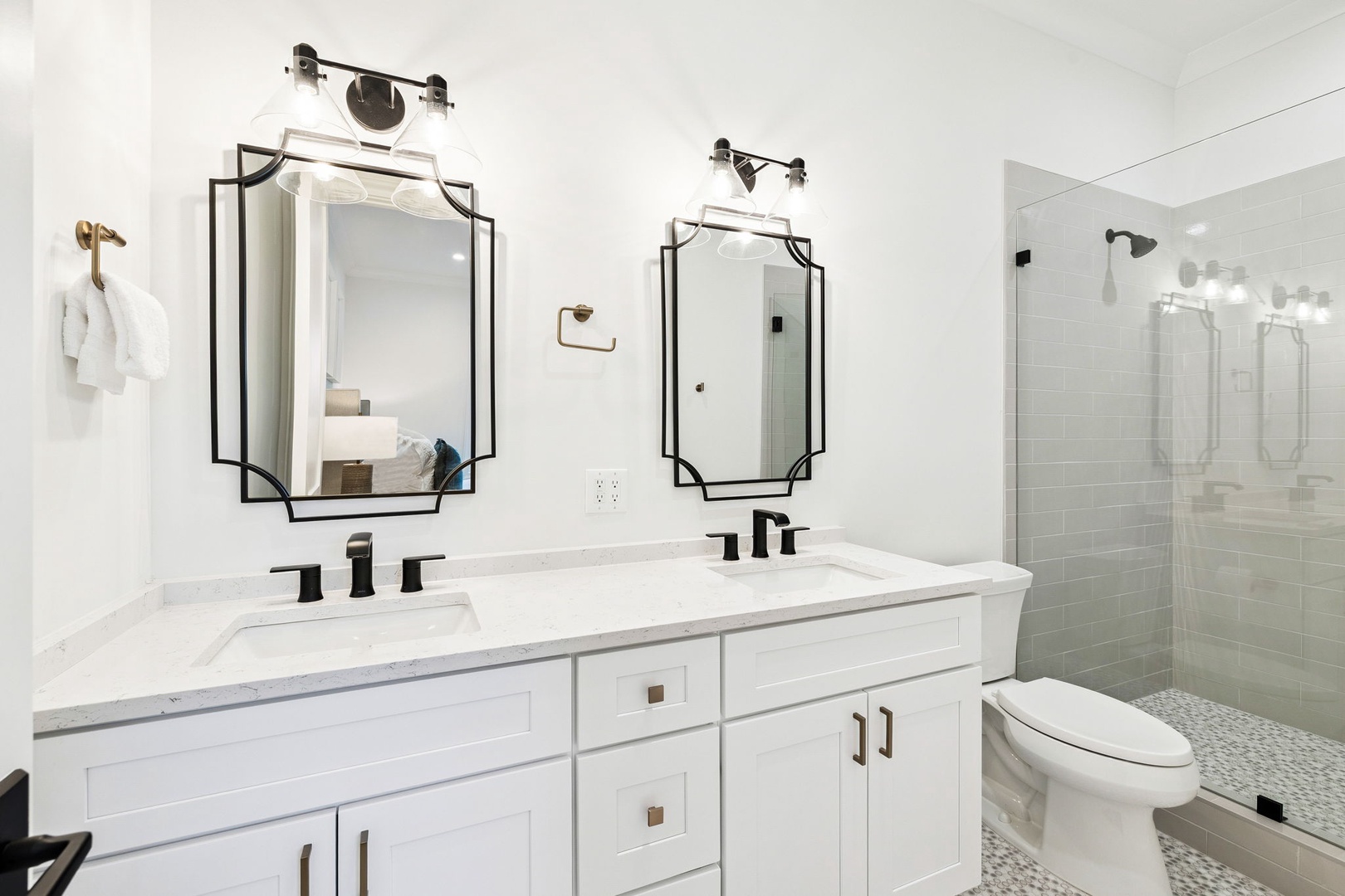 Step into your spa-like bathroom featuring dual vanities, sleek black fixtures, and a spacious glass shower for your daily refresh.