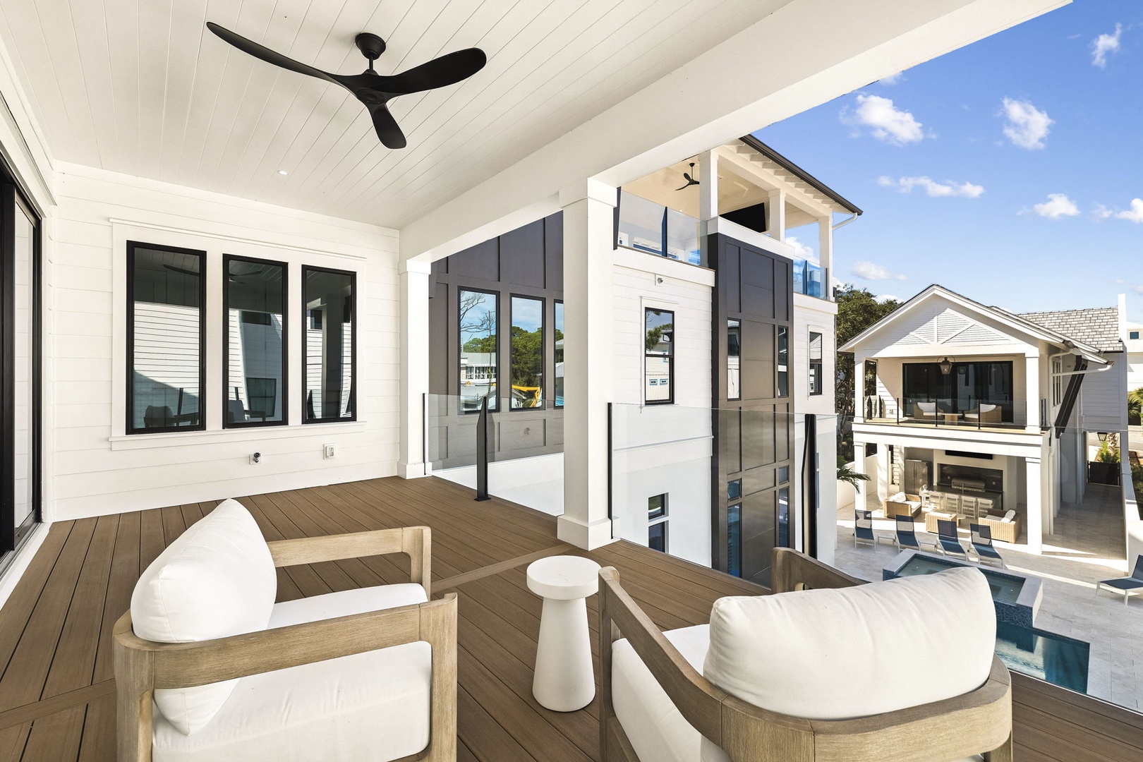 Your covered balcony invites peaceful mornings with chic seating and stunning pool views. Feel the breeze from the ceiling fan as you settle into this open-air retreat.