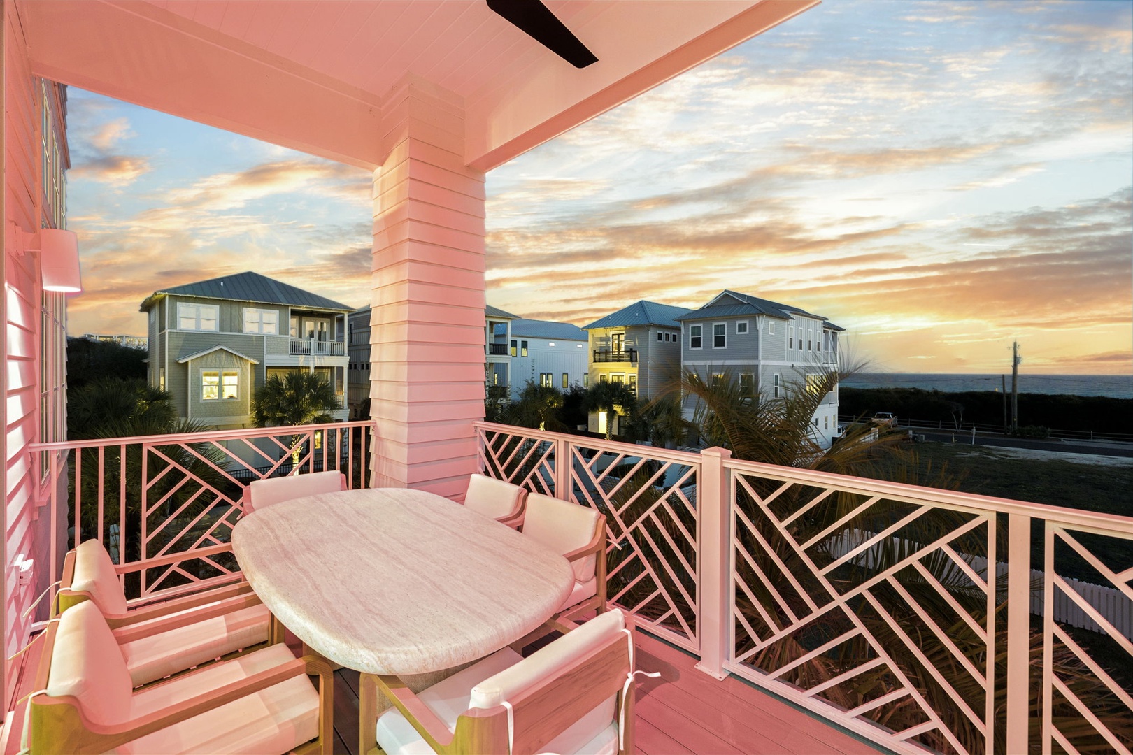 Unwind on your private covered balcony with stunning sunset views over charming beach houses and coastal landscape.