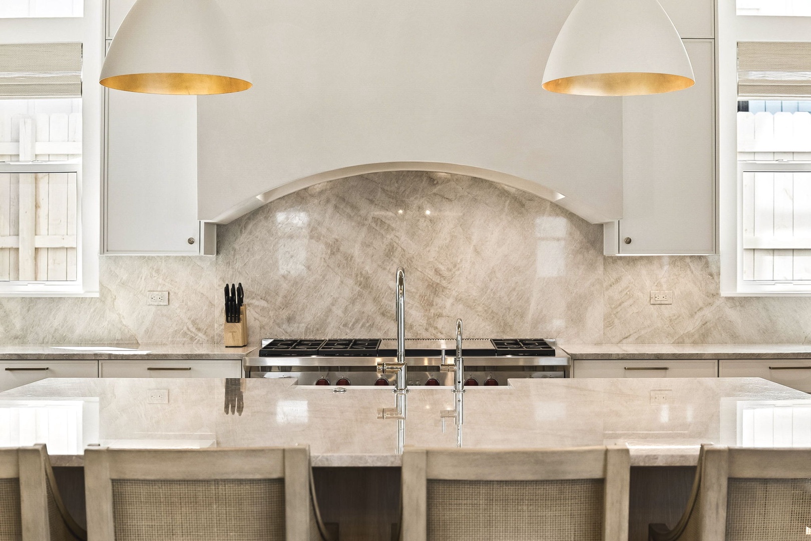 Elegant white cabinetry and warm pendant lighting frame your fully-equipped kitchen with marble backsplash and spacious island—ready for everything from morning coffee to memorable meals.