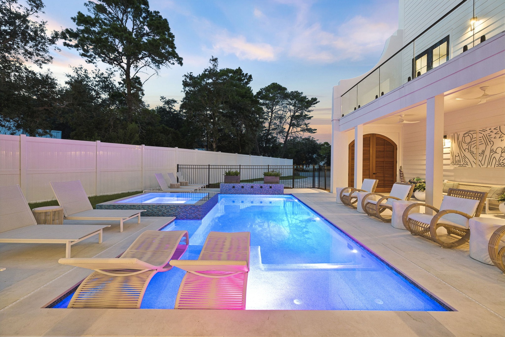 The modern pool features built-in loungers and LED lighting, perfect for twilight relaxation. Chic wicker seating and a sleek outdoor space create your private evening oasis.