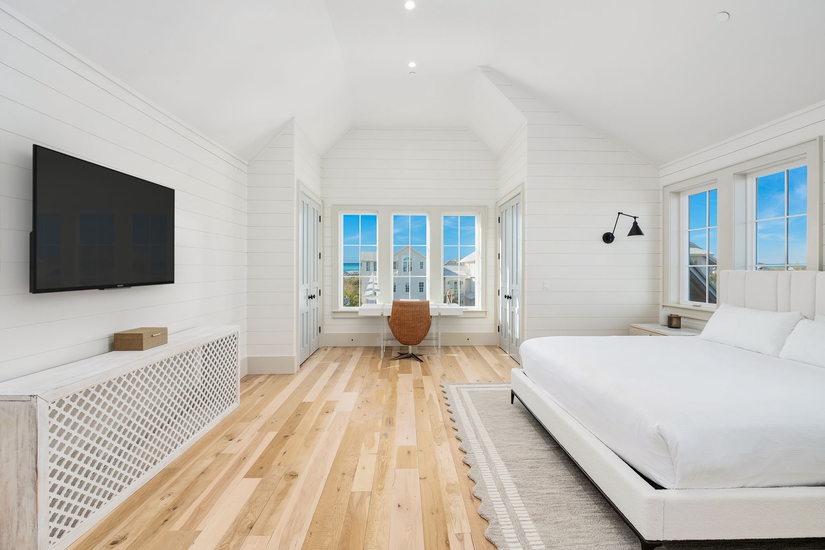 Wake to stunning views in your bright master bedroom, where crisp white linens and warm wood floors create the perfect coastal retreat.