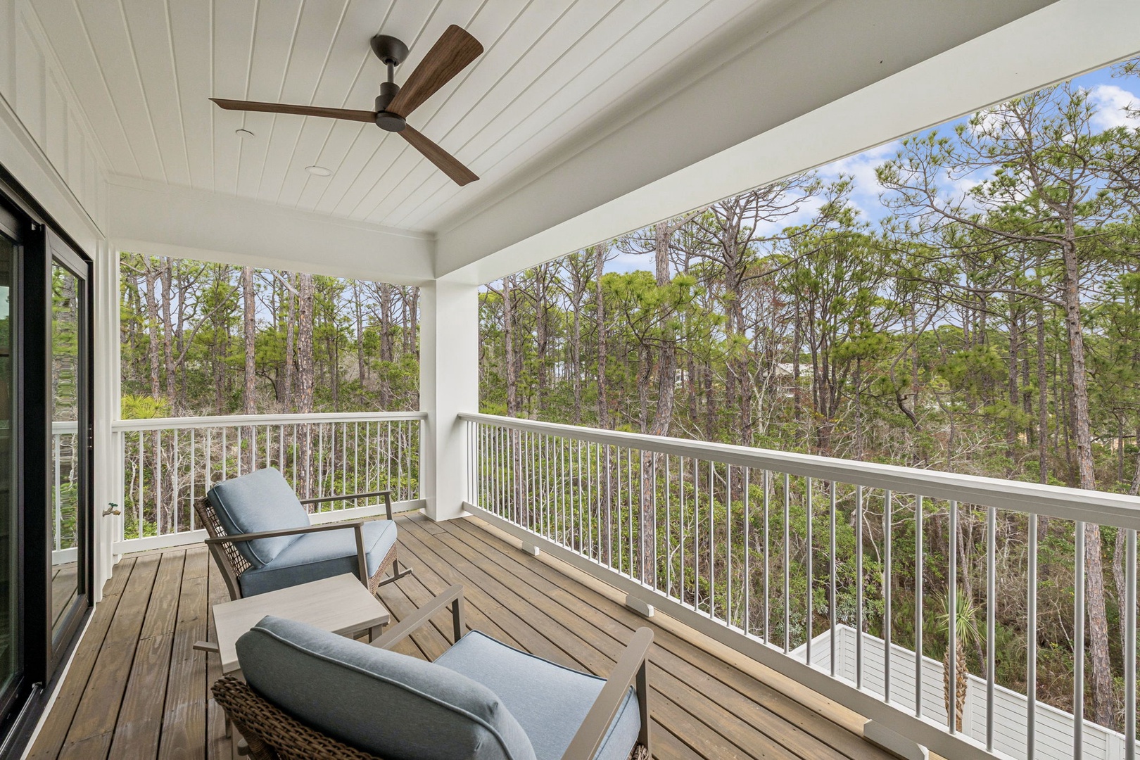 Unwind on your private covered balcony with comfortable seating, ceiling fan, and peaceful forest views for ultimate relaxation.