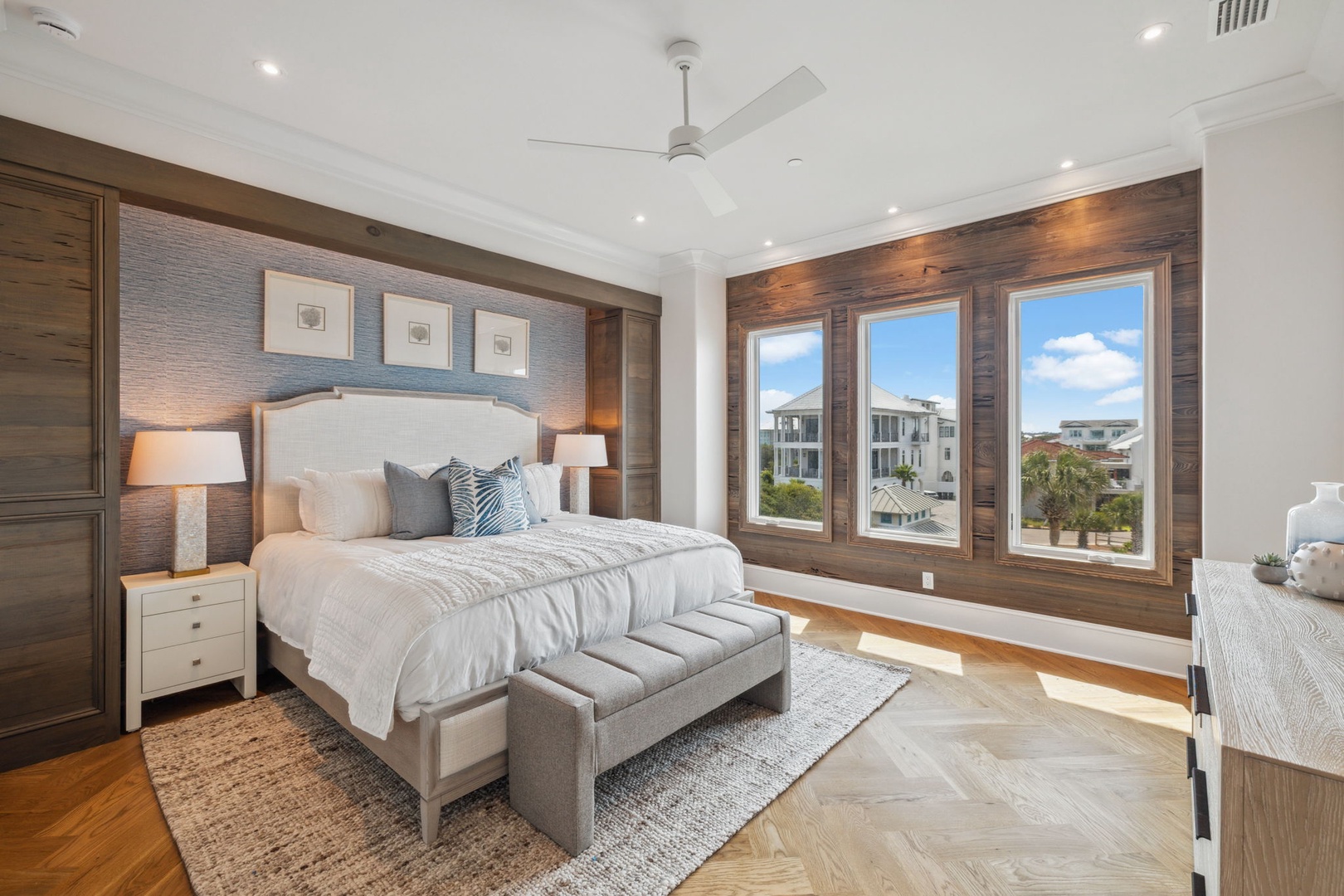 Drift off to peaceful sleep in your spacious master suite, where warm wood accents and plush linens create a serene coastal retreat bathed in natural light.