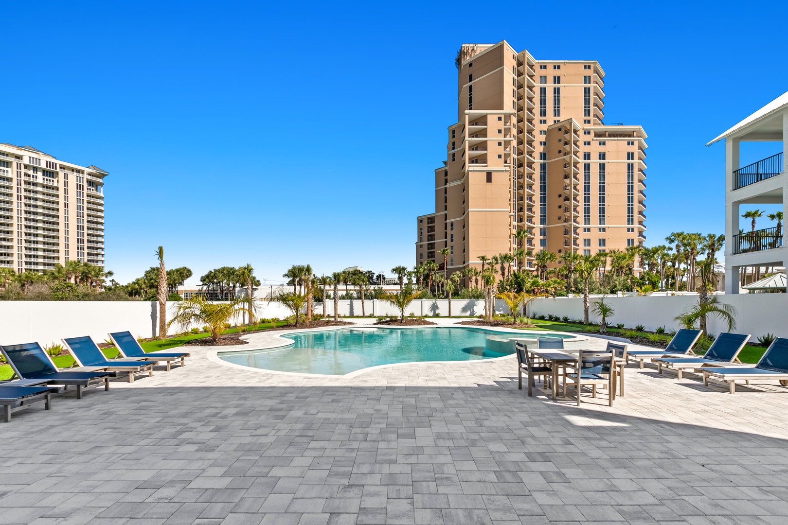 A sparkling pool area framed by swaying palms and modern high-rises creates your perfect beachside retreat, with plenty of loungers for soaking up the Florida sunshine.