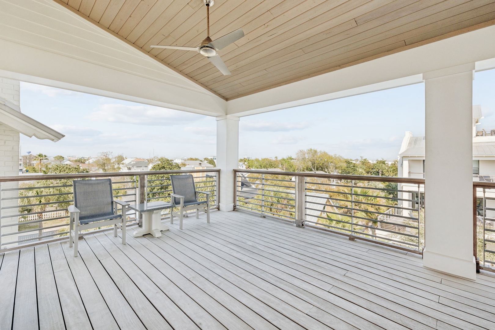 Relax on your private covered balcony with modern seating, ceiling fan, and peaceful treetop views.