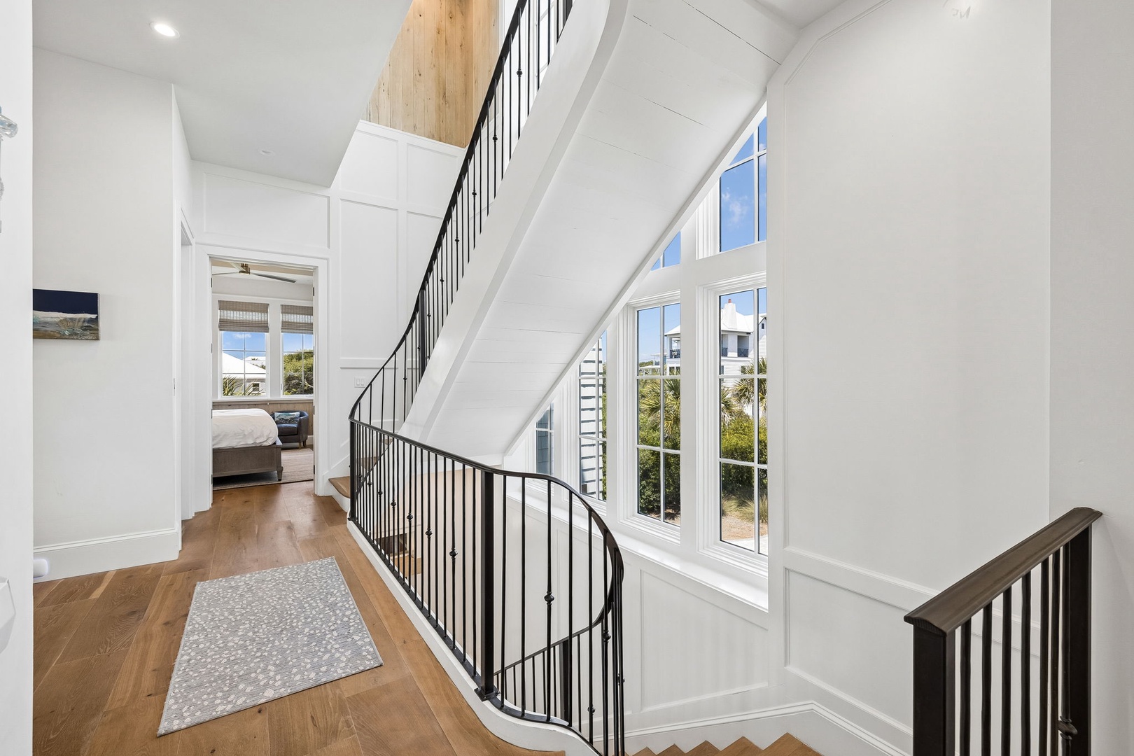 Bright hallway with elegant curved staircase and tall windows inviting natural light throughout your coastal retreat.