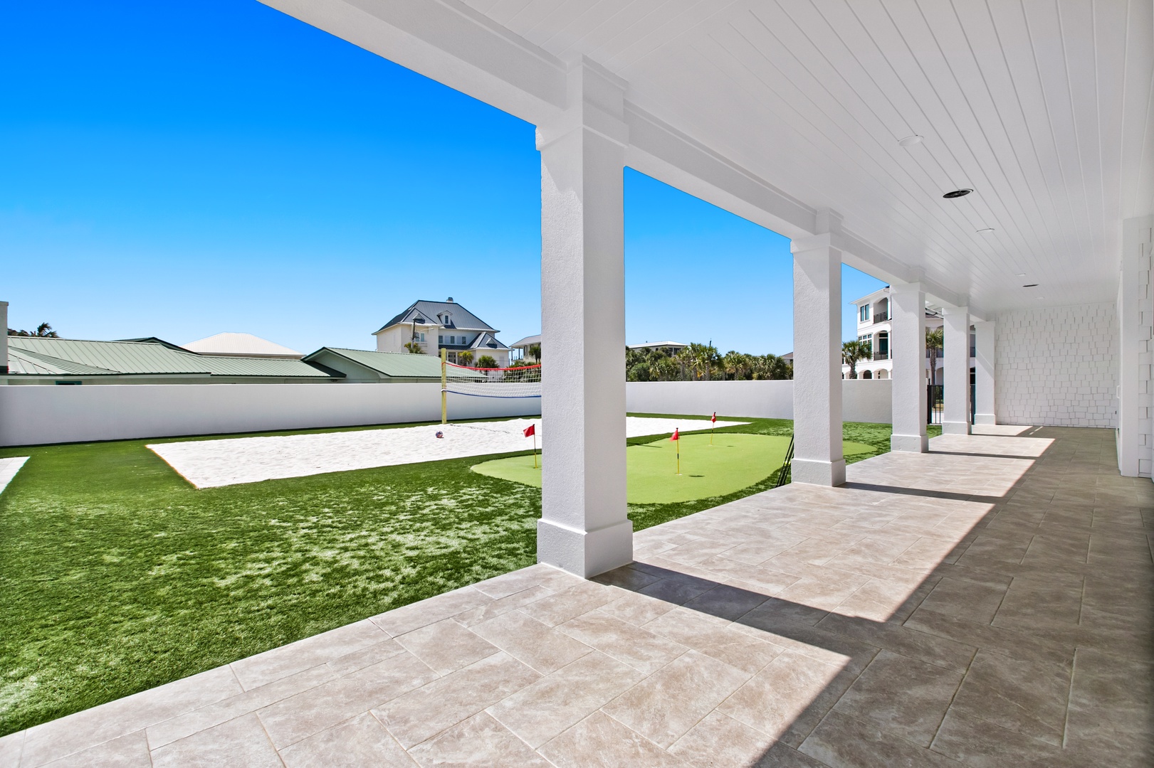 A covered outdoor area with sweeping views of the surrounding neighborhood and nearby homes under clear blue skies.