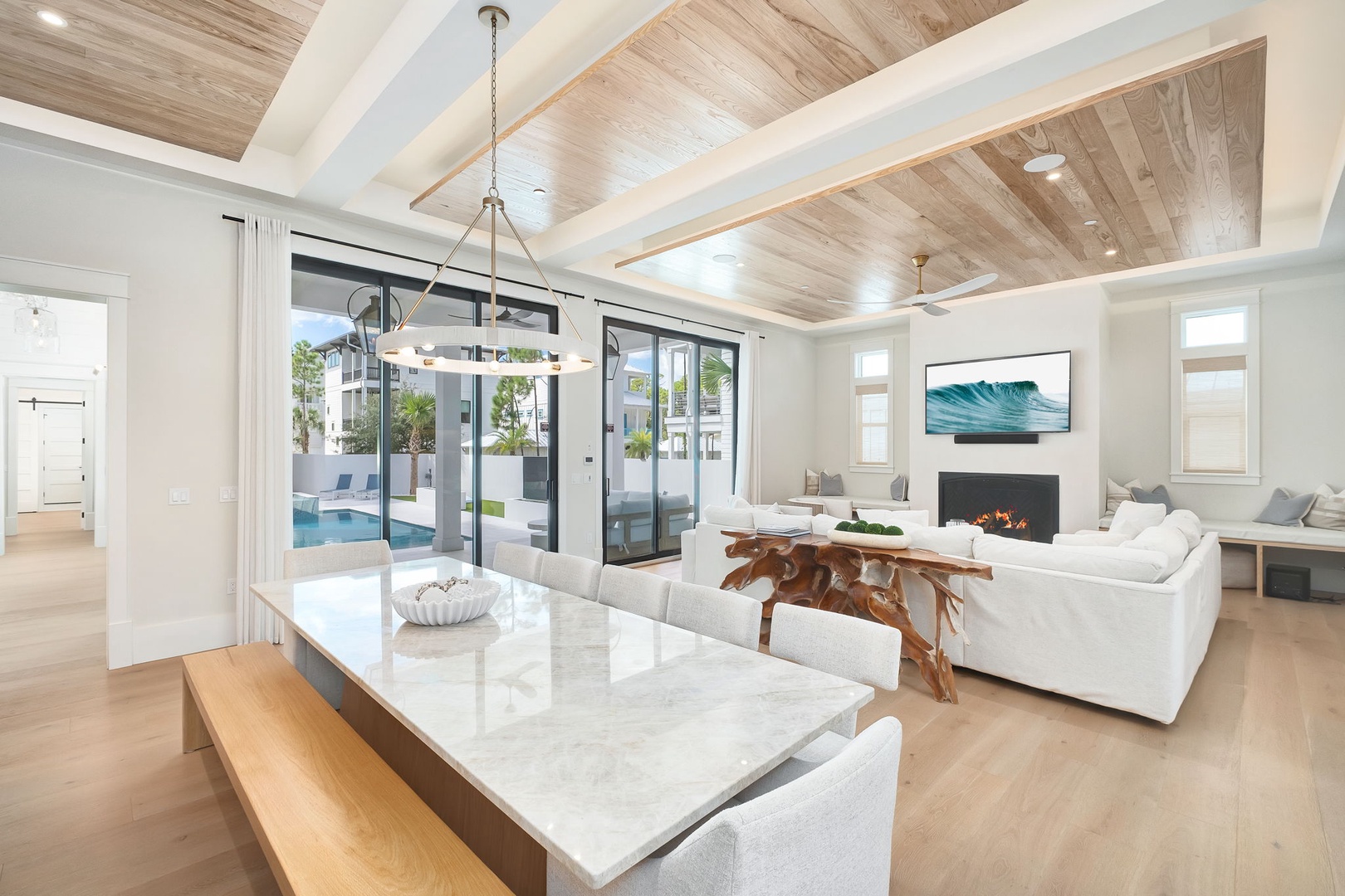 Sink into plush seating beneath stunning wood-paneled ceilings, where natural light floods through floor-to-ceiling doors to your private pool. This open living space invites you to gather, relax, and feel instantly at home.
